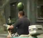 equilibre homme Rouler en scooter avec une pastèque sur la tête