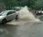 geyser egout eau Une voiture sous une bouche d'égout