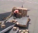 ouvrier Un manutentionnaire lance des colis sur un tapis roulant