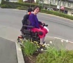 fauteuil roulant Un motard aide une femme en fauteuil roulant