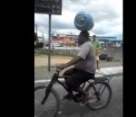 equilibre bouteille Un cycliste avec une bouteille de gaz en équilibre sur la tête