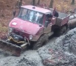 camion Un Unimog tracte des troncs d'arbre dans la boue