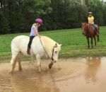 enfant chute fille Un poney joue dans une flaque d'eau