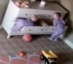 enfant Un enfant aide son frère jumeau à se dégager d'une commode