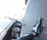 motard Un motard glisse sous la remorque d'un camion