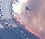 incendie bombardier Un hélicoptère largue de l'eau sur une autoroute au bord des flammes (Californie)