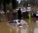 homme voiture toit Un homme bloqué sur le toit de sa voiture dans une inondation