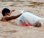 ecole Pour rester au sec, un écolier vietnamien traverse une rivière dans un sac plastique