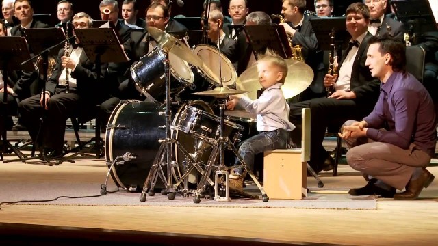 Un enfant de 3 ans joue de la batterie avec un orchestre