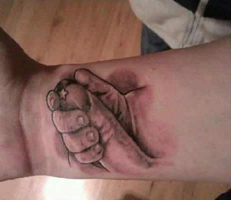 Le tatouage d'une main de bébé qui tient un doigt