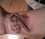 main Le tatouage d'une main de bébé qui tient un doigt