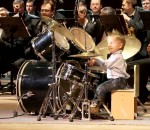 batterie Un enfant de 3 ans joue de la batterie avec un orchestre