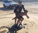 plage dos homme Deux hommes surfent sur le dos d'une tortue
