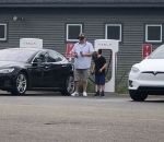 parking voiture Un père et son fils utilisent des masques de réalité virtuelle pendant que la Tesla charge